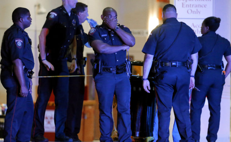 A Dallas police officer covers his face as he stands with others outside the emergency room at Baylor University Medical Center in Dallas. Snipers opened fire on police officers Thursday night, killing some of the officers. (Photo by Tony Gutierrez/AP)