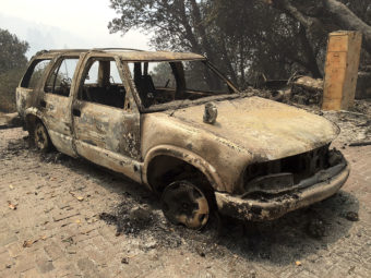 A car destroyed by the Soberanes fire in Big Sur, Calif. Lodge managers and cafe owners there are facing cancelled bookings after fire officials warned that crews will likely be battling the fire for another month. Terry Chea/AP