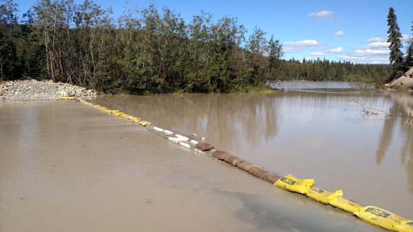 The 8-foot-tall dam that Gorman built earlier this year across the slough was submerged after recent rains raised the Tanana River level. Gorman laid a course of sandbags over the top of the structure to slow the river current and the erosion it causes. “It’s holding,” Gorman says. (Tim Ellis, KUAC – Fairbanks)
