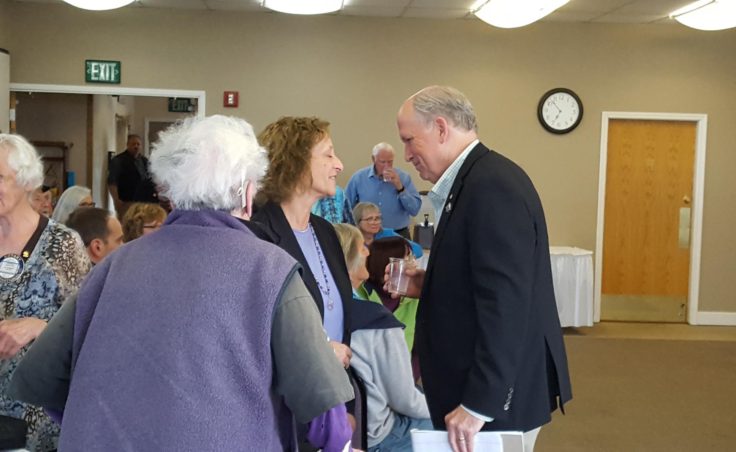 Governor Bill Walker greets Carol Swartz, Director of Kachemak Bay Campus-Kenai Peninsula College, University of Alaska Anchorage at the joint meeting of Homer's two Rotary clubs at Lands End Resort in Homer on Tuesday, August 2. (Shahla Farzan, KBBI)