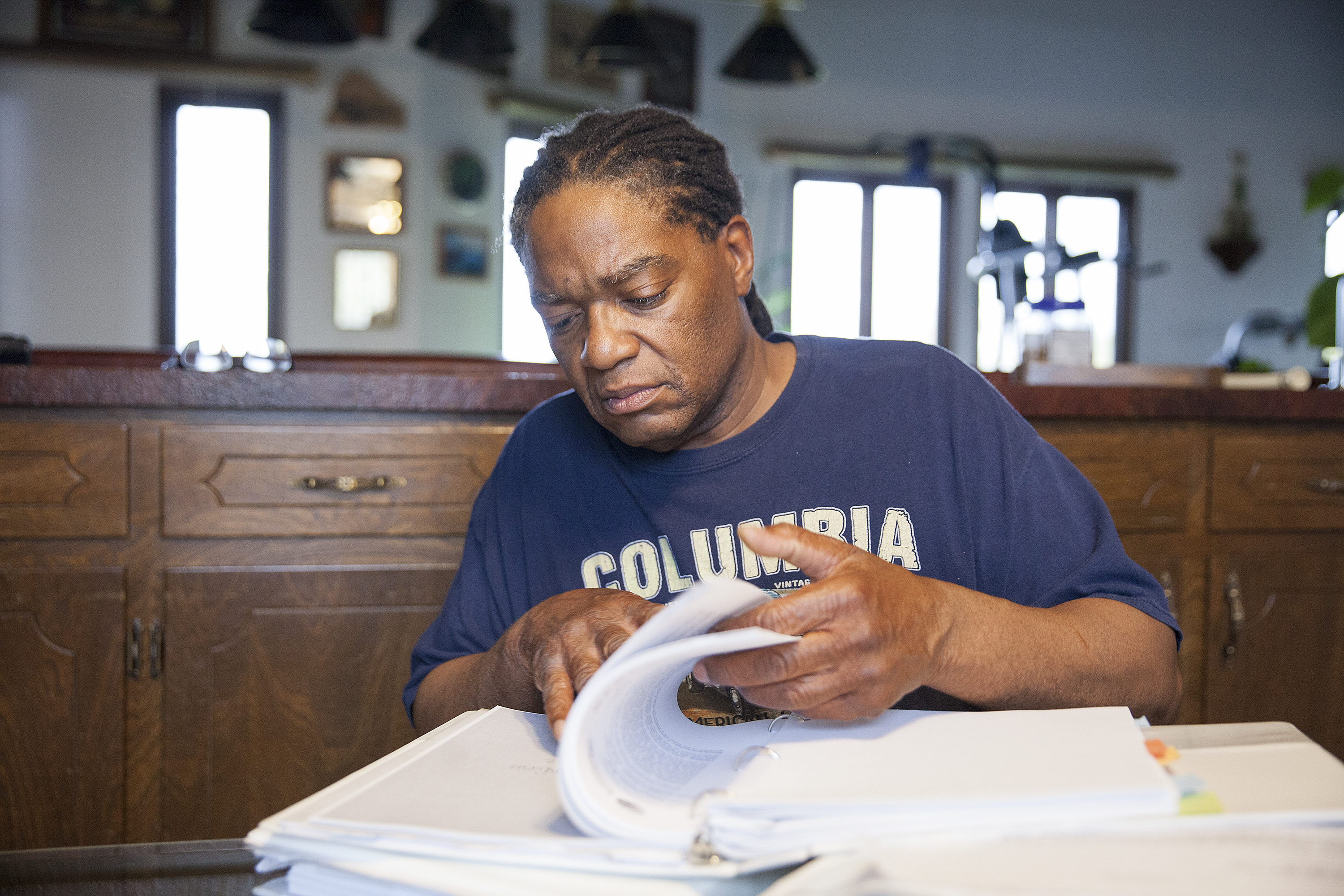 Theodore "Teddy" Burns looks through documents from his discrimination case at his home in Anchorage. Burns' appeal with the Ombudsman Office took eight years to complete. (Photo by Rashah McChesney/ KTOO)