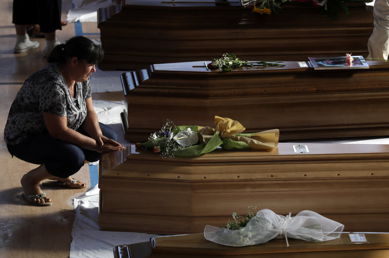 A woman touches a coffin of one of the victims of Wednesday's earthquake inside a gymnasium in Ascoli Piceno. Gregorio Borgia/AP