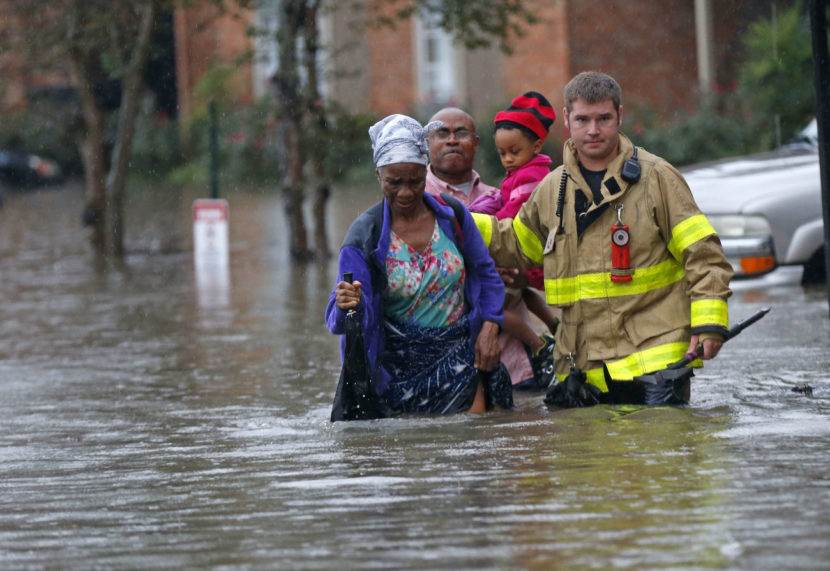 A member of the St. George Fire Department assists residents as they wade through floodwaters from heavy rains in Baton Rouge, La. on Friday. Gerald Herbert/AP
