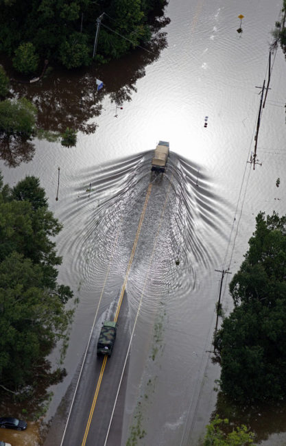 Army National Guard vehicles drive on flooded U.S. Route 190 in Robert, LA. on Saturday. Max Becherer/AP