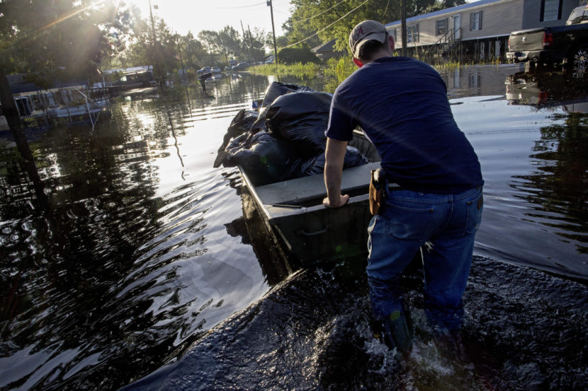 Daniel Stover, 17, moves a boat of personal belongings from a friend's flooded home in Sorrento, La., on Saturday. Max Becherer/AP
