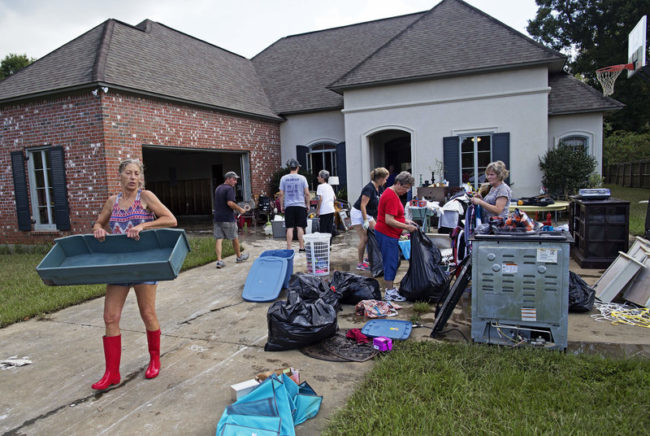 Raven Harelson, 59, (left) carries a drawer to the trash heap in front the home of Sheila Siener, 58, as friends and family help to clean out the flood damaged home in St. Amant, La., on Saturday. Max Becherer/AP
