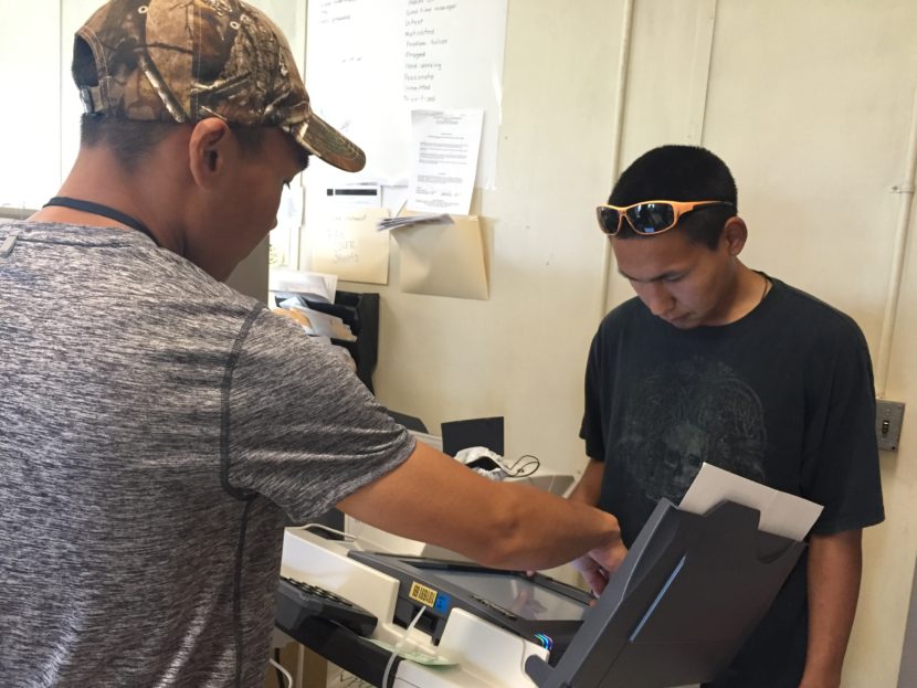 A poll watcher helps Newtok resident Bosco John, 27, vote during Tuesday's election. It was the village's first time using a digital machine. (Photo by Mareesa Nicosia, The 74)