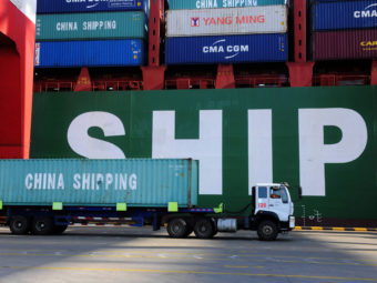 A truck carries a container past a ship at the port in Qingdao, in China's Shandong province on Feb. 15, 2016. China's sagging economy has hurt the shipping industry this year. STR/AFP/Getty Images