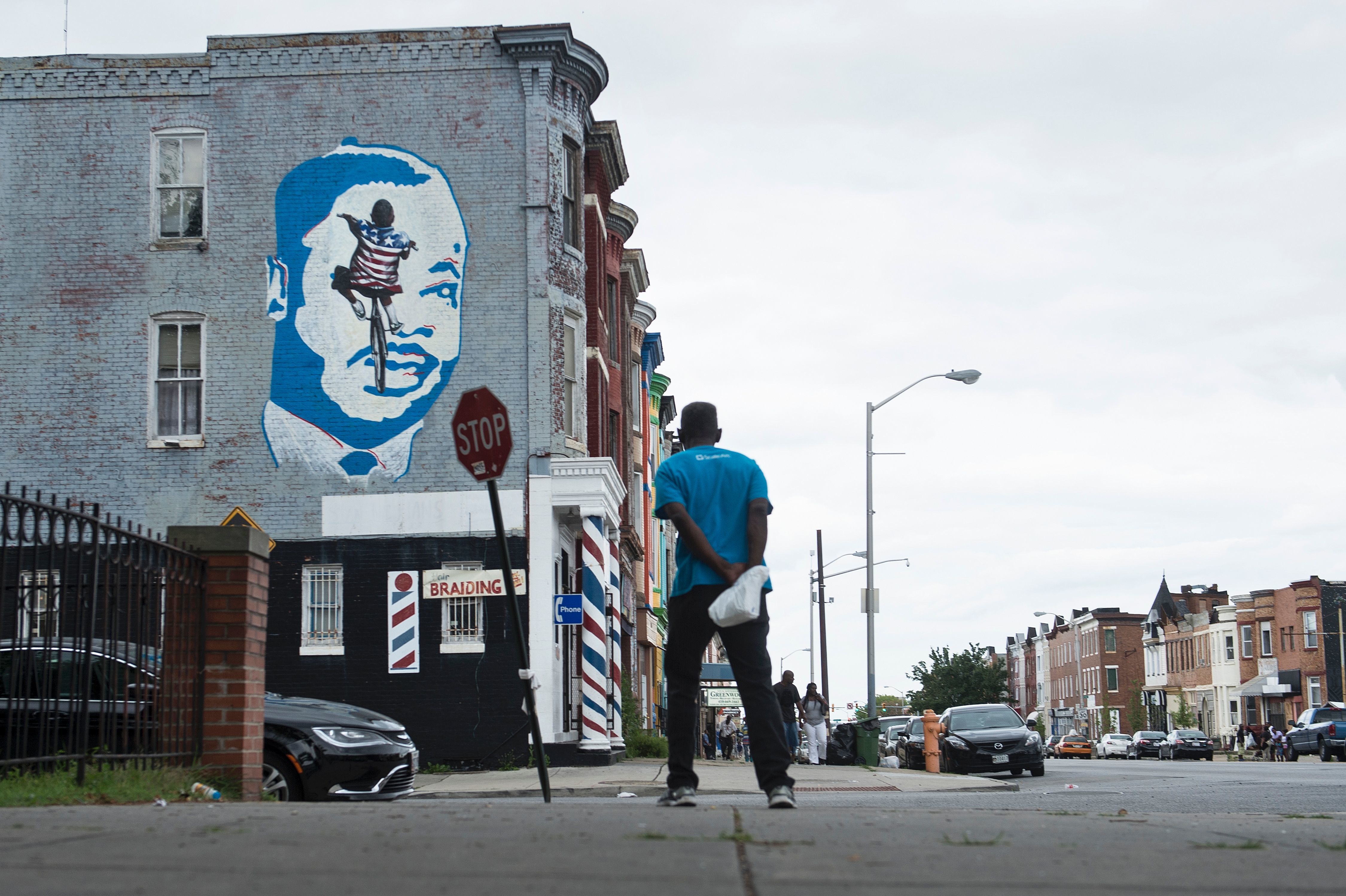 A man looks to a mural of Martin Luther King Jr., on June 23, in the area where riots broke out after the funeral for Freddie Gray last year in Baltimore.