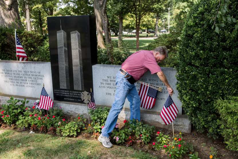 Russell Mercer replaces old U.S. flags with new ones at the Flushing World Trade Center Memorial at Flushing Cemetery in New York City. His stepson, Scott Kopytko, was killed on Sept. 11. Alex Welsh for NPR