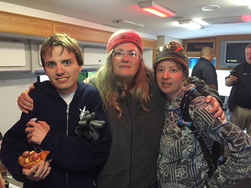 Ryan Harvey (left) grabs a slice of pizza inside the Juneau Police Department's Mobile Incident Command Center after he was found in good condition on Thursday. The blue hoodie was given to him after he was found.