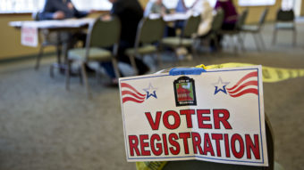 A voter registration sign hangs near a table where residents fill out paperwork at a polling location during the presidential primary vote in Waukesha, Wis., on April 5. (Photo by Daniel Acker/Bloomberg via Getty Images)