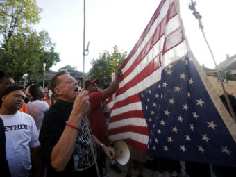 Father Michael Pfleger of St. Sabina Church hangs the American flag upside down outside his church Aug. 31 as demonstrators protest the uptick in homicides across Chicago. Thirteen people were fatally shot over the weekend, bringing the city's annual toll to at least 500. (Photo by Joshua Lott/Getty Images)