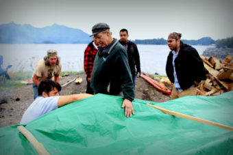 Master carver Steve Brown oversaw the steaming, while Jerrod Galanin takes a look under the tarp. (Photo by Emily Russell/KCAW)