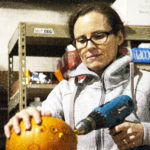 Amy Karpstein uses a drill to carve small holes into her pumpkin at Juneau Makerspace in Lemon Creek on Monday, October 24, 2016. Karpstein was one of seven people using the space Monday night during an open studio night. (Photo by Tripp J Crouse/KTOO)