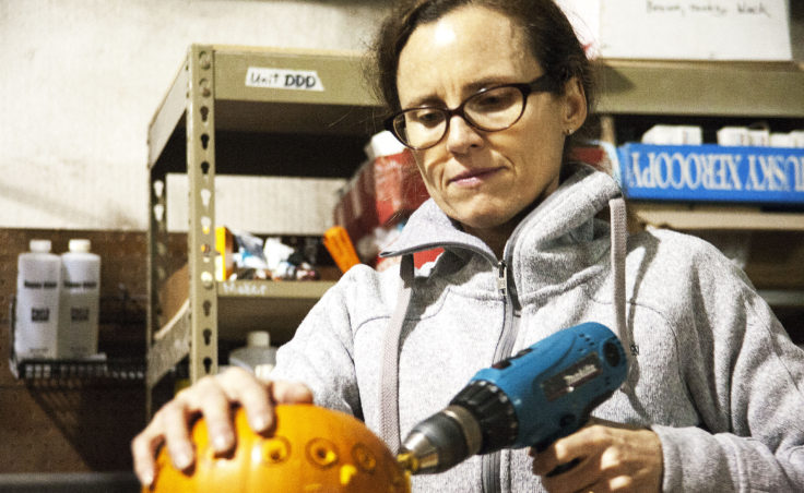 Amy Karpstein uses a drill to carve small holes into her pumpkin at Juneau Makerspace in Lemon Creek on Monday, October 24, 2016. Karpstein was one of seven people using the space Monday night during an open studio night. (Photo by Tripp J Crouse/KTOO)