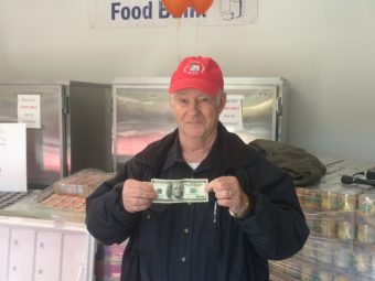 Jim Wilcox holds up a $100 donation on Saturday.
