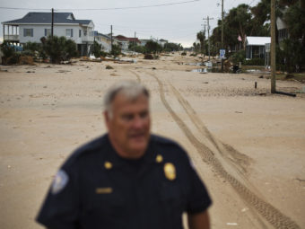Chief of Police George Brothers walks along what used to be a four-lane national scenic byway that's now covered in sand after Hurricane Matthew hit the beach community of Edisto Beach, S.C., Saturday. David Goldman/AP