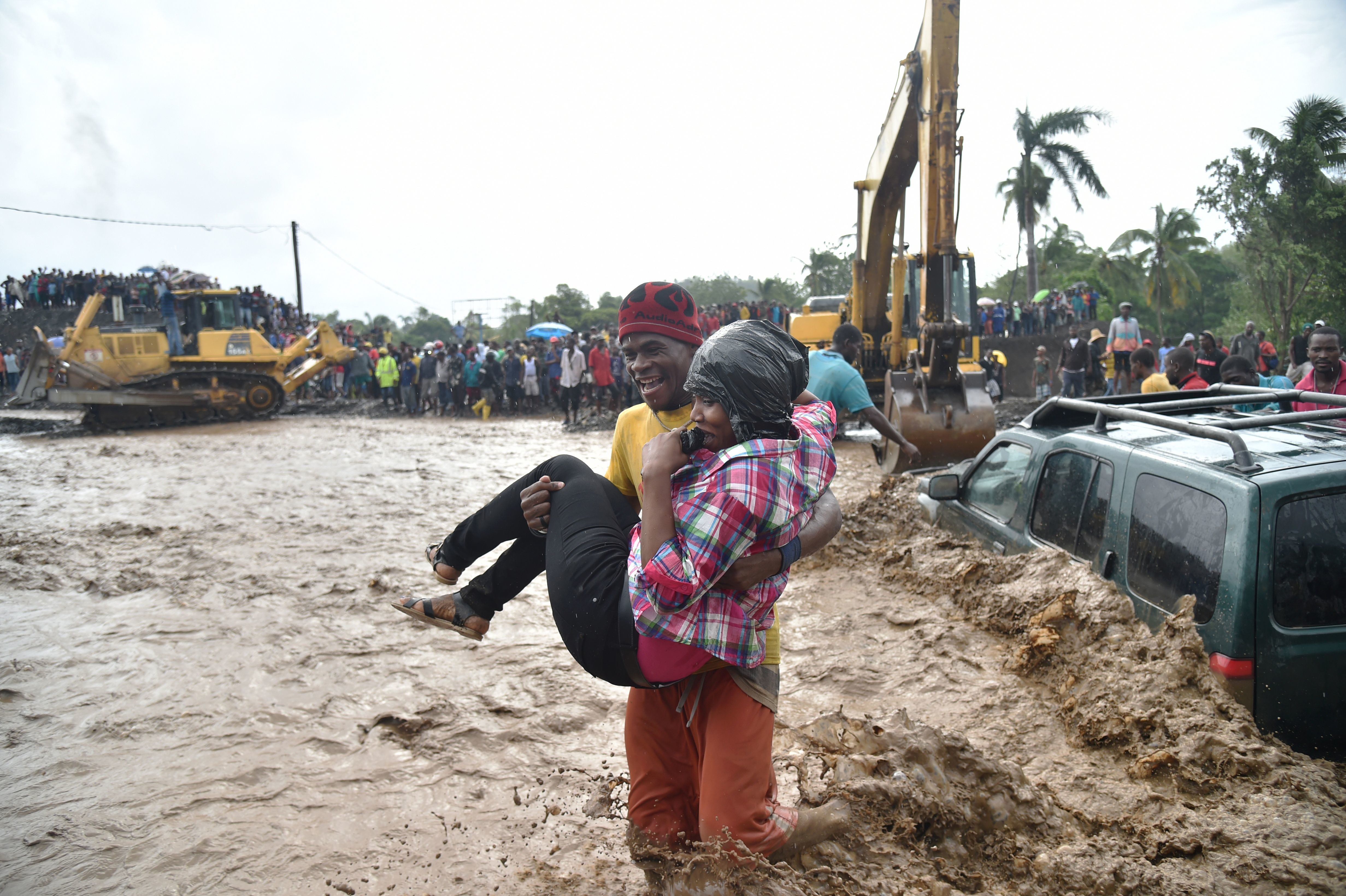 People help each other across the river La Digue in Petit Goave, Haiti, on Wednesday, a day after Hurricane Matthew raked the island nation. (Photo by Hector Retamal/AFP/Getty Images)