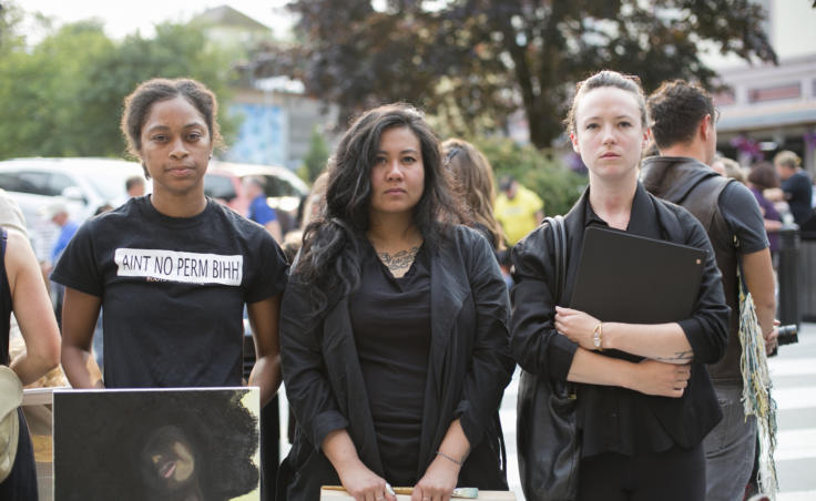 Three women dressed in black stand on a street corner. Juneau artists Jennifer Gross, Christianne Carrillo, and Cate Ross stand outside the Sealaska Heritage Institute following a demonstration protesting the budget cuts to the Alaska State Council on the Arts on Tuesday, July 9, 2019. (Photo by Annie Bartholomew/KTOO)