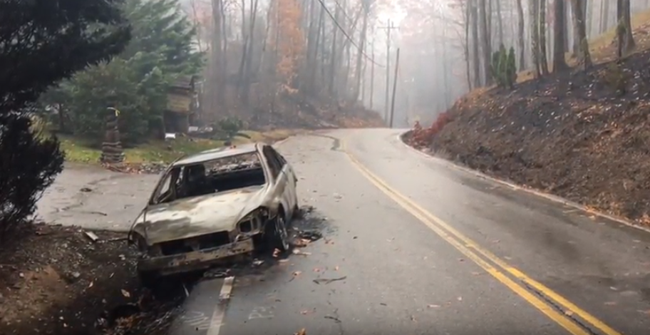 A burned-out car sits on the side of a road near Gatlinburg, Tenn. (Video screenshot from the Tennessee Department of Transportation)
