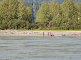Kayakers rest near the U.S.-Canadian border on the Stikine River, marked by a line of cleared trees. (File photo by KFSK)