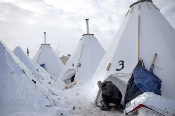 Jacob Brooks makes adjustments to one of the camp's many "tarpees," a winterized teepee made of tarp with a built-in chimney, designed by Paul Cheokoten Wagner. There are roughly 60 tarpees around various camps now, and Wagner has fundraised enough for another 20 more. Celia Talbot Tobin for NPR