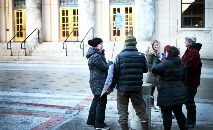 Protesters chat Monday morning, Jan. 30, 2017, in front of the Alaska State Capitol Building in downtown Juneau, Alaska. Protest organizers Jill Weitz and Dan Kirkwood estimate that about 175 people stood at the steps to support refugees and immigrants in the wake of President Donald Trump's executive orders heavily restricting immigration. (Photo by Tripp J Crouse/KTOO)