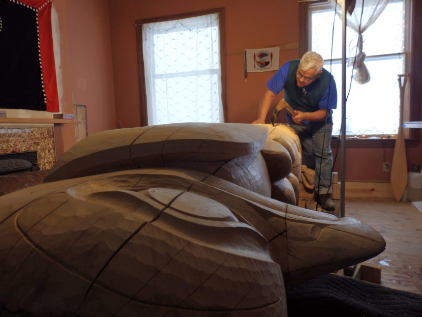 Wayne Price works on a 12 foot tall totem pole in his Haines studio. (Photo by Emily Files/KHNS)
