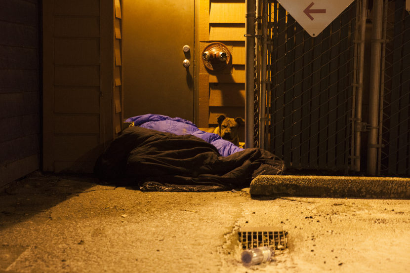 Two people and a dog curl up near a boiler room on Shattuck Way on Jan. 20, 2017, in downtown Juneau, Alaska. (Photo by Rashah McChesney/Alaska's Energy Desk)