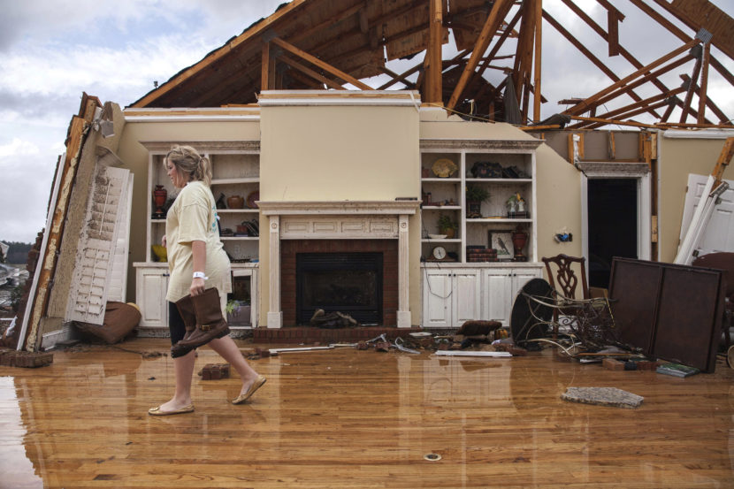 Jenny Bullard carries a pair of boots from her home that was damaged by a tornado in Adel, Ga. (Photo by Branden Camp/AP)