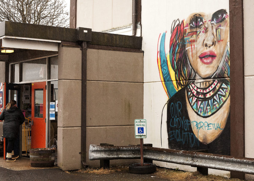 A woman enters the Juneau Arts & Culture Center on Wednesday, February 15, 2017. Will Kozloff's unfinished mural can be seen on the outside the JACC's exterior. The Anchorage artist was invited to Juneau to work on set pieces for the Goveror's Awards for the Arts in January. (Photo by Tripp J Crouse)