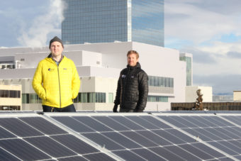Stephen Trimble and Chase Christie of Arctic Solar Ventures show off the company's largest installation to date: an 86-panel commercial installation in downtown Anchorage. (Photo by Rachel Waldholz/Alaska's Energy Desk)