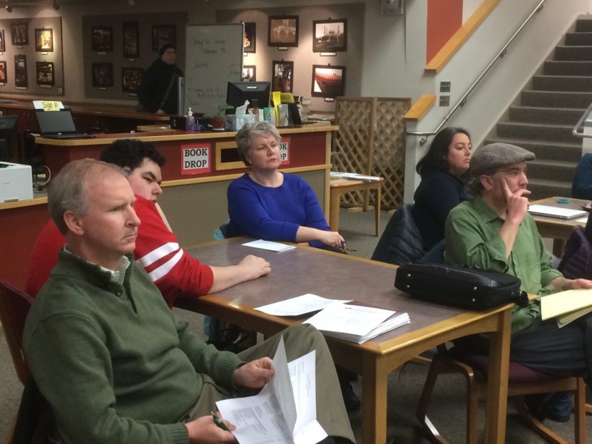 School Board President Brian Holst, left, and other audience members listen during the meeting.