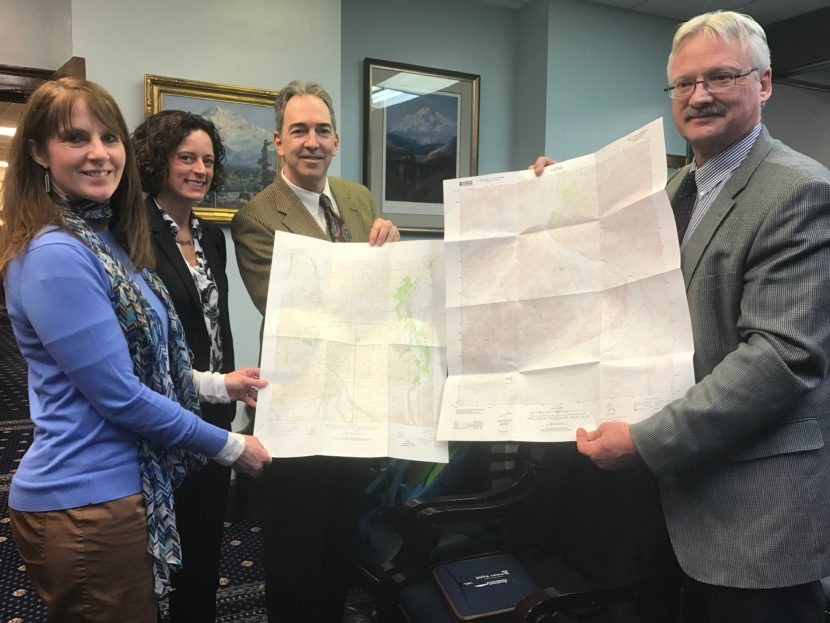 Sen. Natasha von Imhof, Kevin Gallagher, Ed Fogels hold new topographic maps of Alaska created through the Alaska Mapping Initiative.