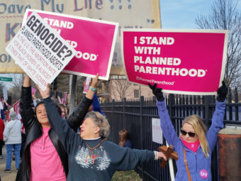 Planned Parenthood supporters and an opponent of the organization try to block each other's signs during a protest and counterprotest Saturday in St. Louis. Jim Salter/AP