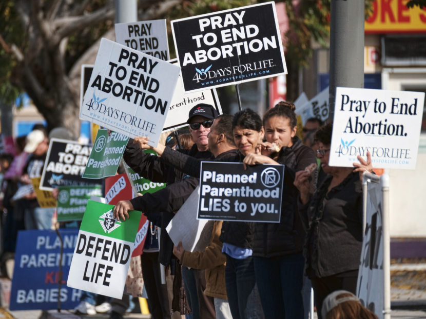 Protesters display their signs outside a Planned Parenthood health center in Los Angeles on Saturday. Together with protesters in other cities across the U.S., they gathered to demand the organization be stripped of its federal funding.