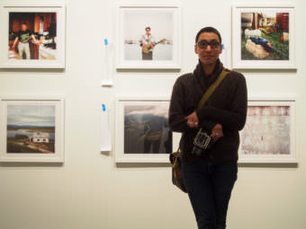 Photographer Brian Adams stands before a few of the 50 images featured in the Anchorage Museum’s exhibition for his “I Am Inuit” project. (Photo by Zachariah Hughes/Alaska Public Media)