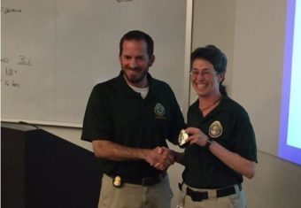 FBI counselor Michael Siegling presents Unalaska's Jennifer Shockley with her new deputy police chief badge at the FBI National Academy in Virginia. (Photo by CREDIT FBI National Academy)