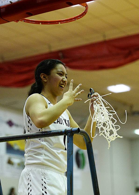 Ketchikan's AJ Dela Cruz holds the title net and four fingers representing her fourth straight 4A girls Region V championship win with the Lady Kings.