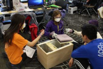 ANSEP Academy students have to wear masks and gloves when operating the heat lamps and using the various materials. (Photo by Wesley Early, Alaska Public Media – Anchorage)