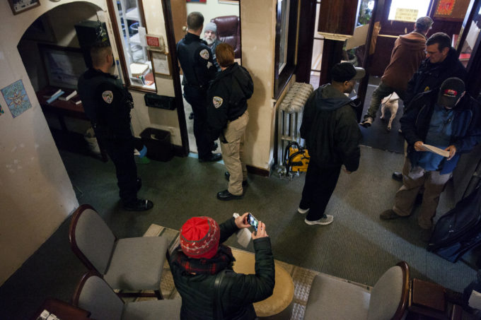 Police, aid workers, journalists and tenants of the Bergmann Hotel gather in the lobby as the building is cleared and boarded up on Friday, March 10, 2017 in Juneau, Alaska.