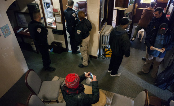Police, aid workers, journalists and tenants of the Bergmann Hotel gather in the lobby as the building is cleared and boarded up on Friday, March 10, 2017 in Juneau, Alaska.