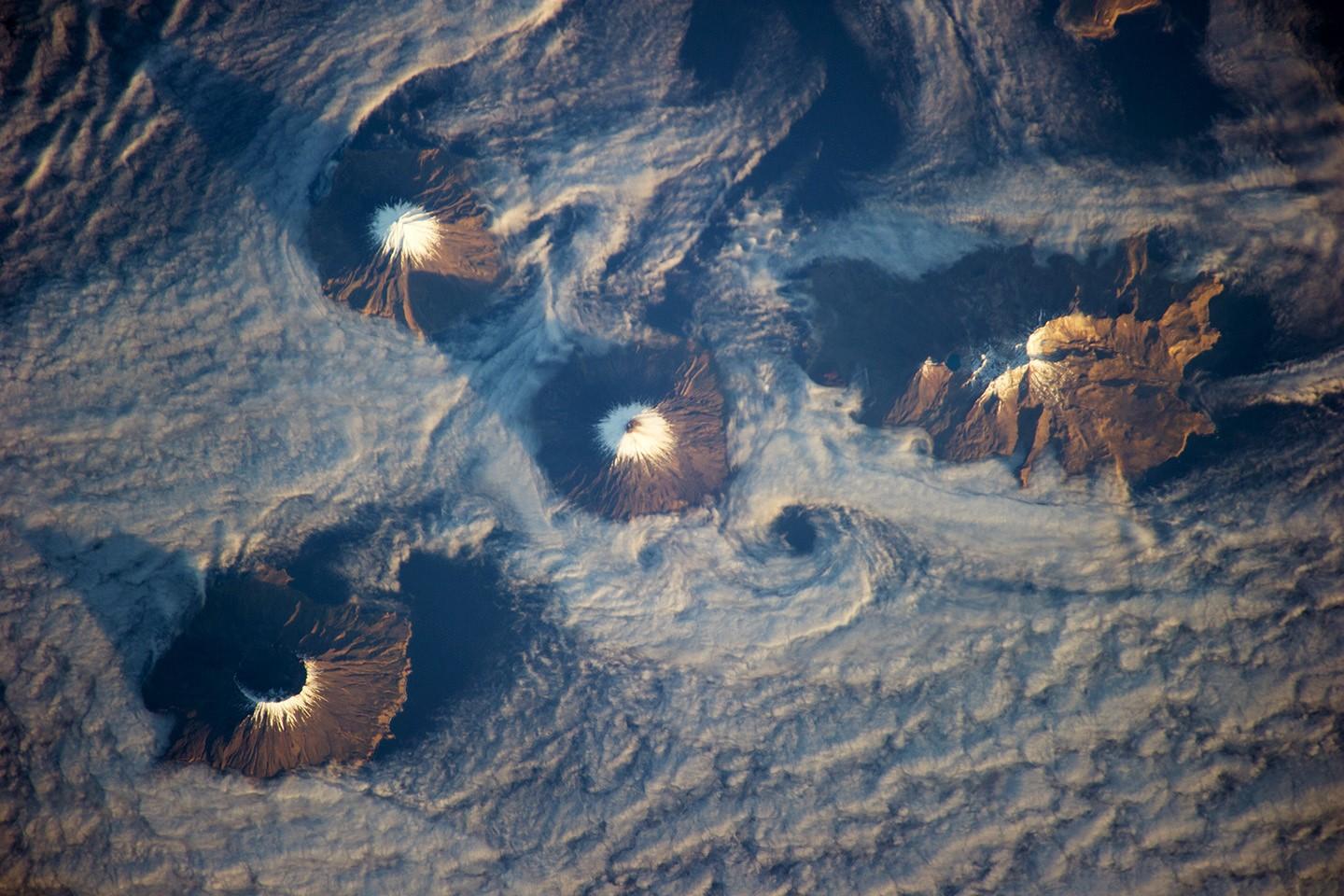 An aerial view of the Islands of the Four Mountains in the central Aleutians. (Photo by NASA Earth Observatory)