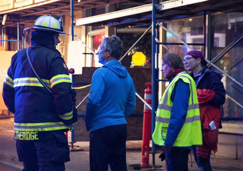 A firefighter talks with store owner Art Sutch on Saturday night, April 15, 2017, as emergency personnel work the scene of a fire in the 200 block of Seward Street, downtown Juneau. (Photo courtesy of Tripp J Crouse)