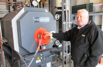 Airport Manager Mike Carney stands next to the Ketchikan International Airport’s new biomass wood-pellet boiler last summer.