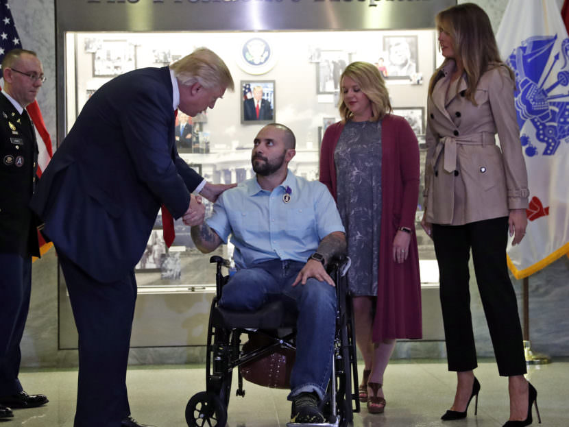 President Donald Trump shakes hands with U.S. Army Sgt. First Class Alvaro Barrientos, after awarding him with a Purple Heart , as first lady Melania Trump, right, stands with Tammy Barrientos second from right, at Walter Reed National Military Medical Center, Saturday. Alex Brandon/AP