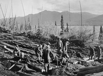 Black soldiers serving in the Army's segregated units often didn't have enough heavy equipment, so they had to work with hand tools and their ingenuity for such tasks as building "corduroy roads" with logs to stabilize the roadway through boggy muskeg areas. (Photo courtesy National Film Board of Canada)