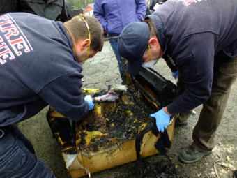 Student investigators discover a burned, purple plastic bin melted into the framework of a chair during a recent fire investigator training exercise at Juneau’s Hagevig Regional Fire Training Center. (Photo by Matt Miller/KTOO)