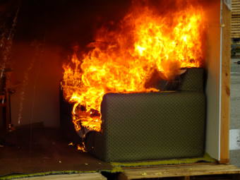 A couch erupts in flame during room during a recent fire investigator training exercise at Juneau’s Hagevig Regional Fire Training Center. (Photo by Matt Miller/KTOO)